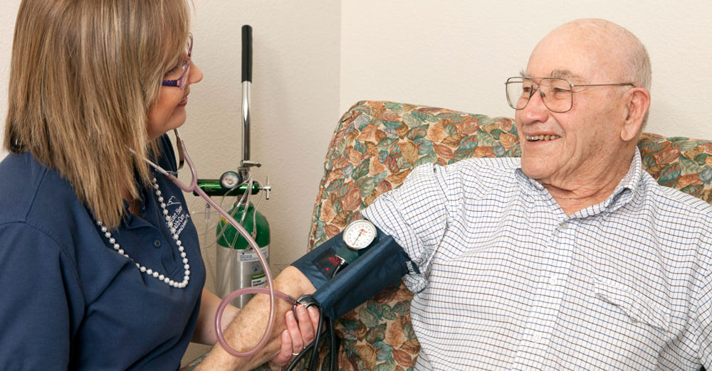 caregiver taking an older man's blood presure